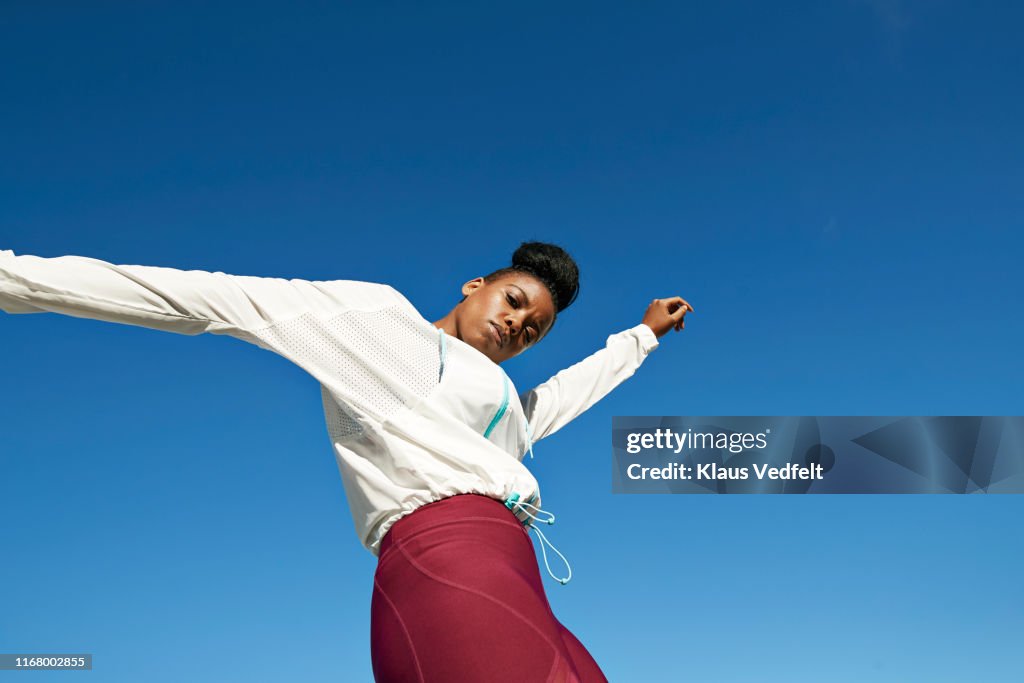 Portrait of young sportswoman against clear blue sky