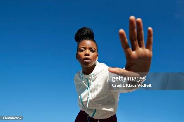 portrait of female athlete gesturing against clear blue sky - mano tesa foto e immagini stock