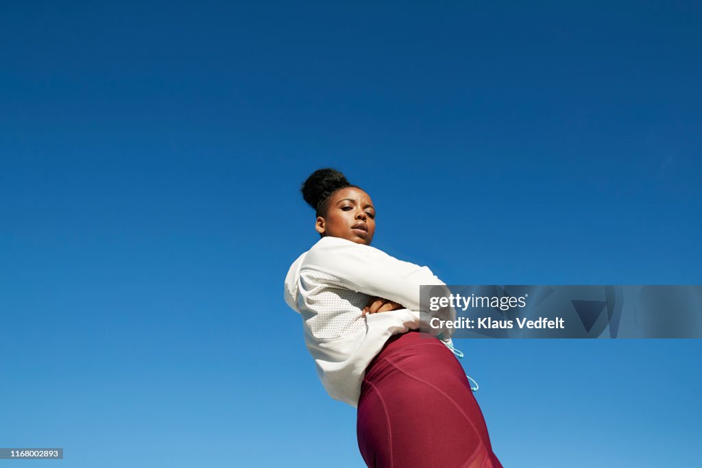 Young woman wearing sports clothing against clear blue sky on sunny day