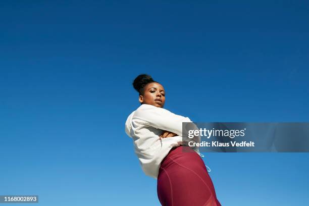 young woman wearing sports clothing against clear blue sky on sunny day - black jacket photos et images de collection