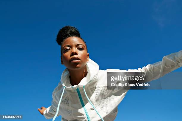 directly below shot of female athlete wearing white jacket against clear blue sky - portrait fashion woman stock-fotos und bilder