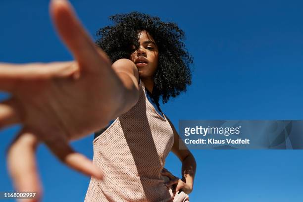 portrait of frizzy sportswoman gesturing against clear blue sky - estirándose fotografías e imágenes de stock