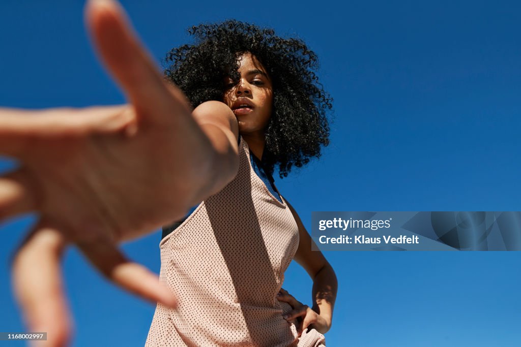 Portrait of frizzy sportswoman gesturing against clear blue sky