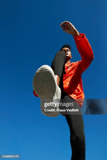 sportsman running against clear blue sky on sunny day - running shoes sky stock-fotos und bilder