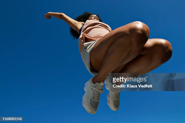 female athlete jumping against clear blue sky - running shoes sky stock pictures, royalty-free photos & images