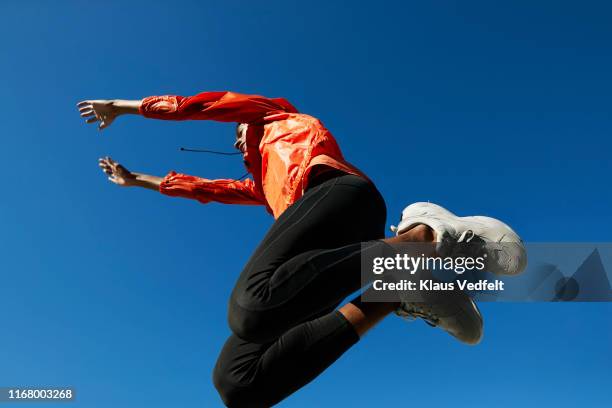 fit sportsman jumping against clear blue sky - orange jacket stock pictures, royalty-free photos & images