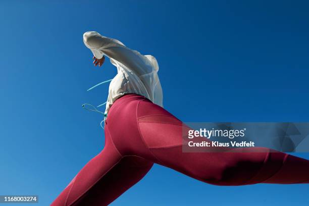 sportswoman in sportswear jumping against clear blue sky - leggings imagens e fotografias de stock