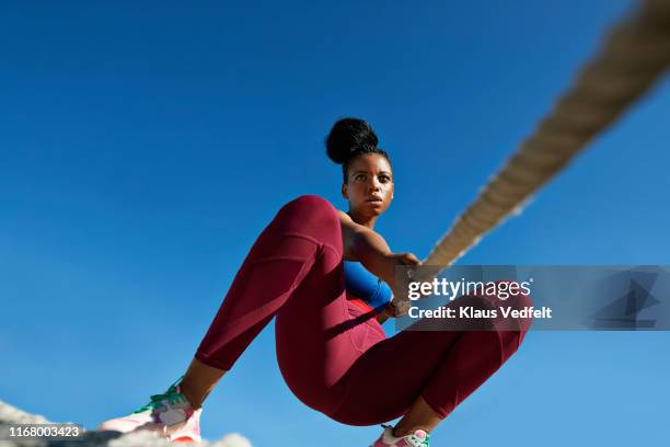 sportswoman pulling rope against clear blue sky - legging stock-fotos und bilder