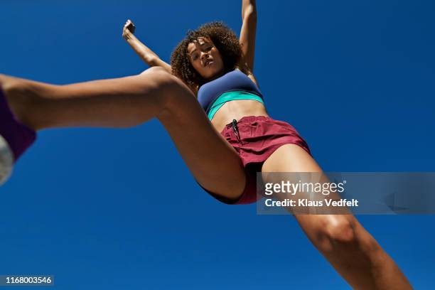 young sportswoman jumping against clear sky - arms raised to sky stock pictures, royalty-free photos & images