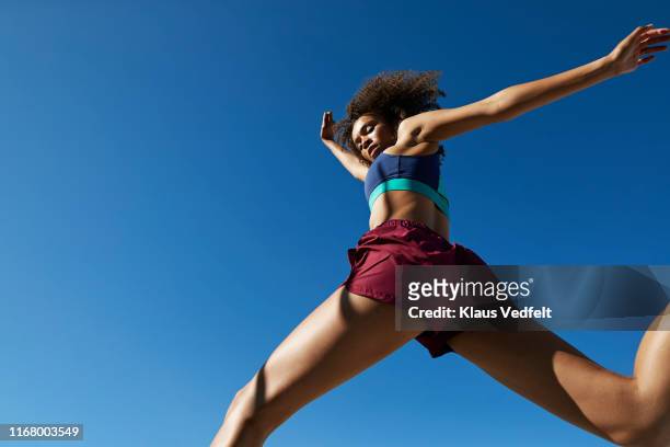 young woman exercising against clear sky - sportivo foto e immagini stock