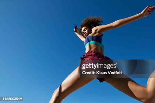 Young woman exercising against clear sky Young woman exercising against clear sky