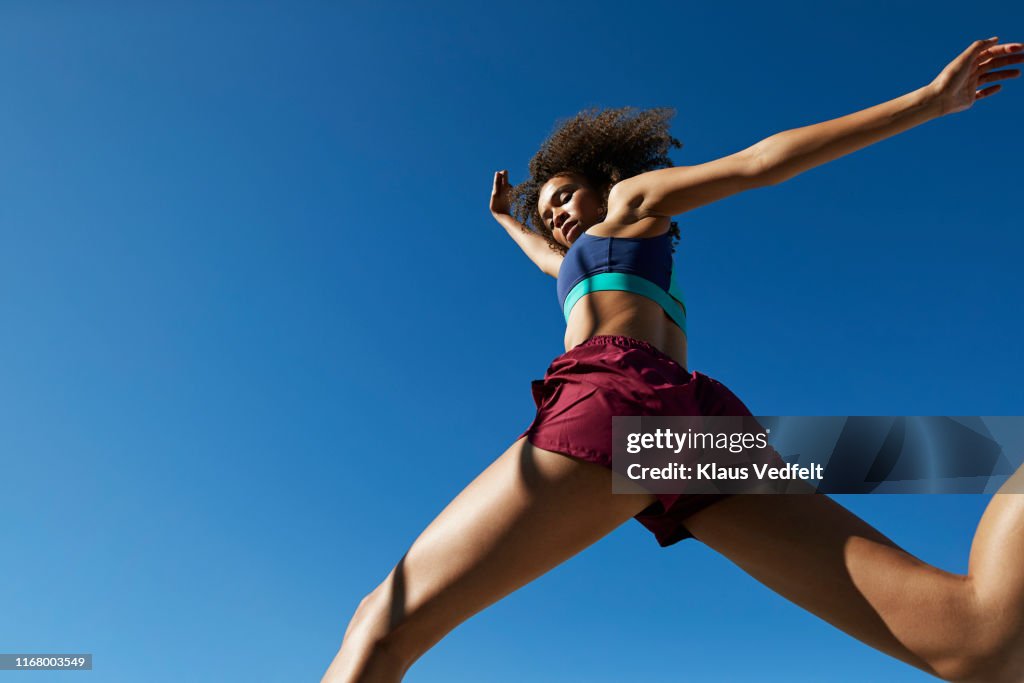 Young woman exercising against clear sky