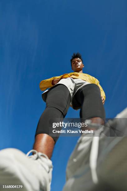 portrait of sportsman standing against blue sky - running shoes sky stock-fotos und bilder