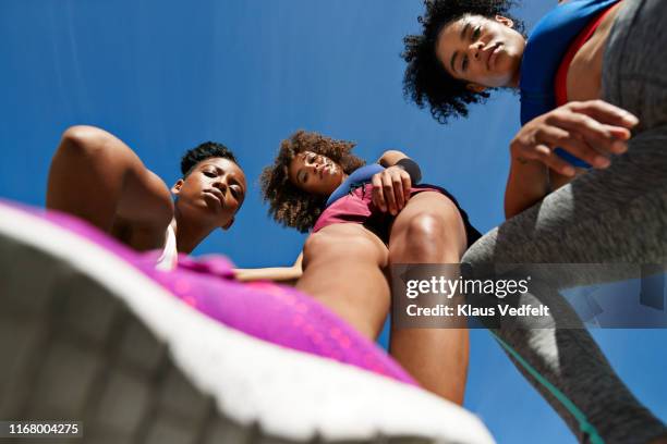 directly below shot of female athletes against blue sky - running shoes sky stock pictures, royalty-free photos & images