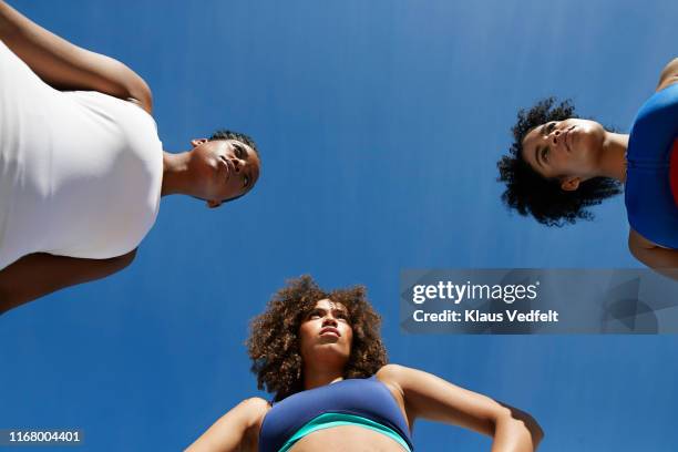 confident athletes in sportswear looking away against blue sky - blue sky friends photos et images de collection