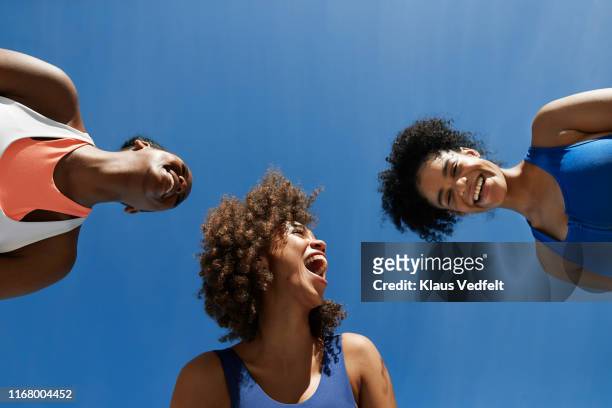 cheerful female athletes in sportswear against blue sky - viewpoint stock-fotos und bilder