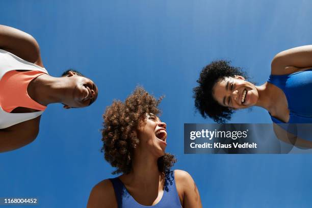 cheerful female athletes in sportswear against blue sky - happy people summer fashion foto e immagini stock