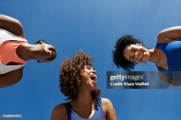 cheerful female athletes in sportswear against blue sky - treinamento imagens e fotografias de stock