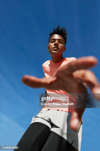 portrait of male athlete gesturing against blue sky - blue leggings stock pictures, royalty-free photos & images