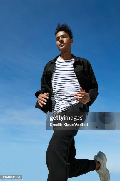 fashionable man running against blue sky - striped jacket stock-fotos und bilder