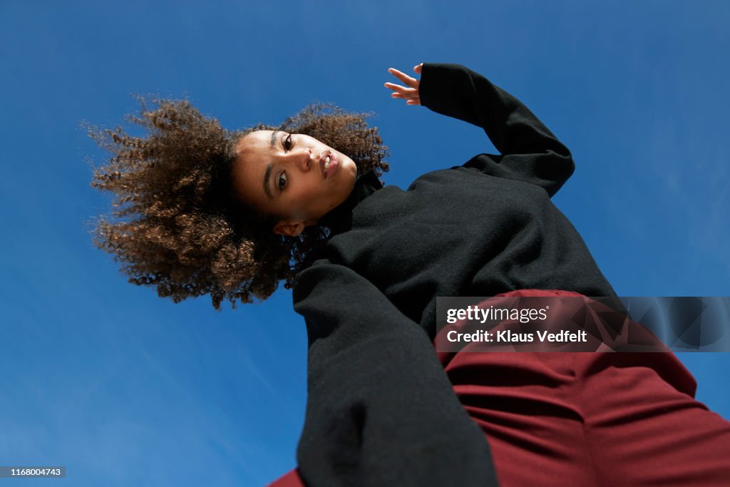 Portrait of young woman with head cocked against blue sky