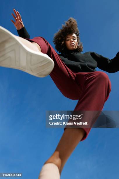 portrait of woman wearing casuals against blue sky - saltare foto e immagini stock