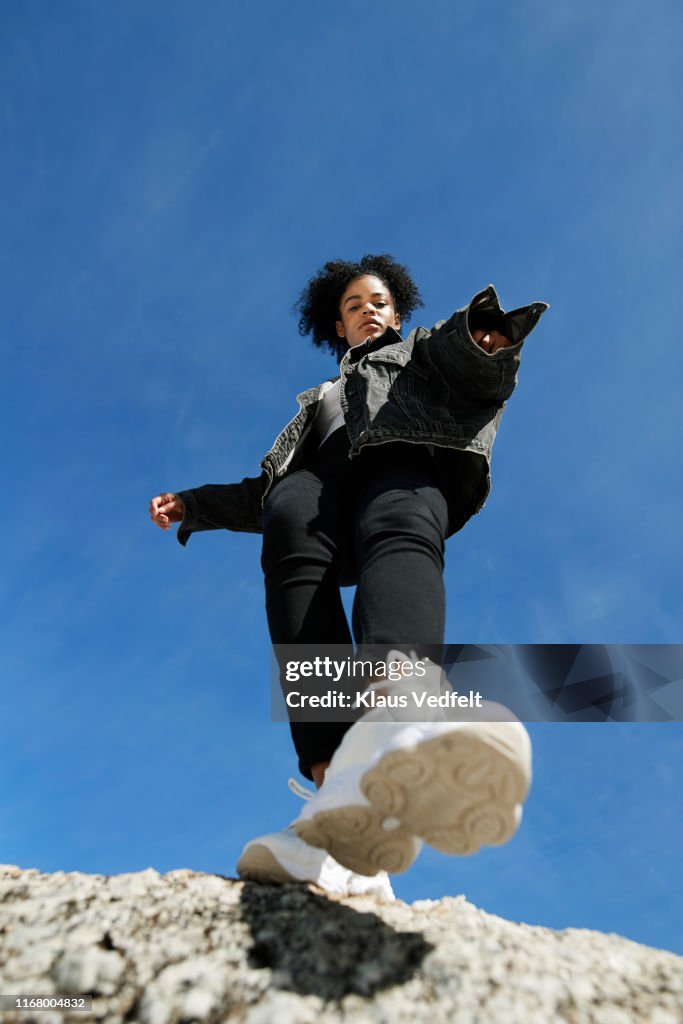 Young woman wearing denim jacket against blue sky