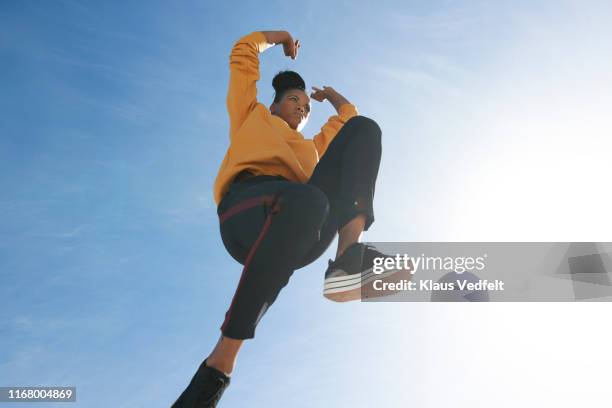 directly below shot of carefree woman jumping against blue sky - low angle view ストックフォトと画像