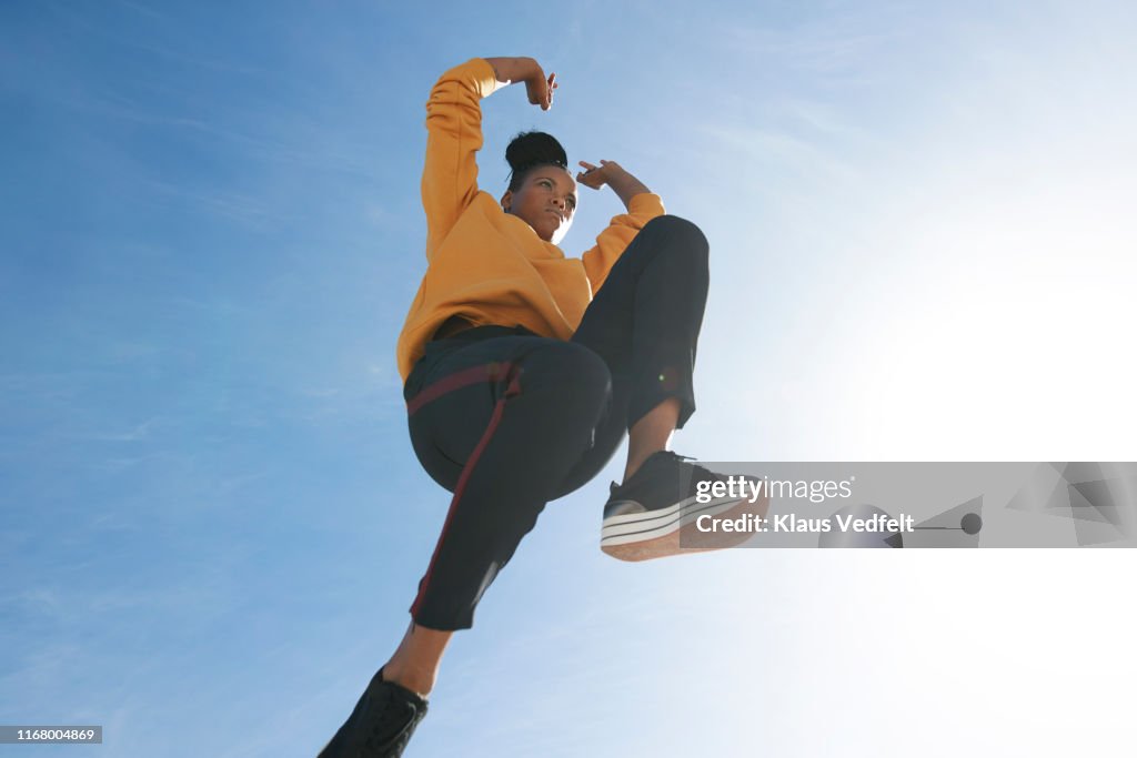 Directly below shot of carefree woman jumping against blue sky
