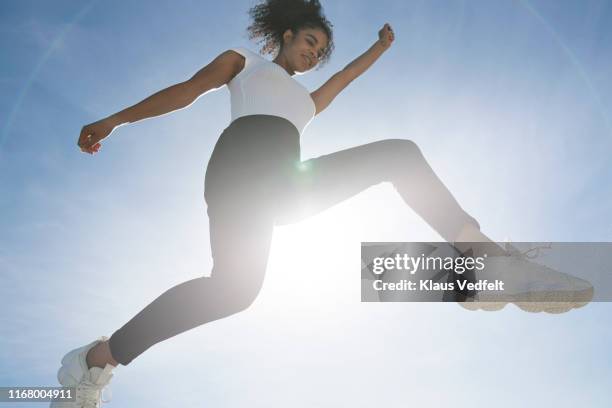 carefree woman jumping against blue sky on sunny day - jumping sun bildbanksfoton och bilder