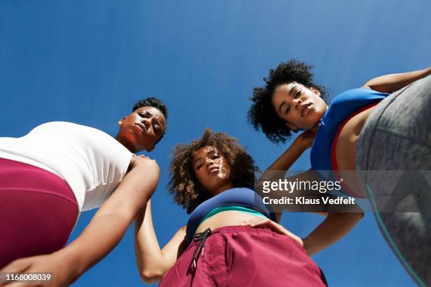 portrait of female athletes in sportswear against blue sky - low angle view stock pictures, royalty-free photos & images