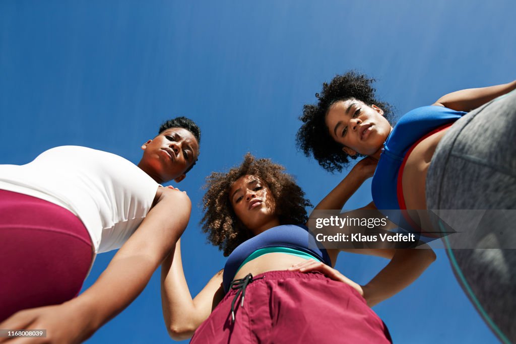 Portrait of female athletes in sportswear against blue sky