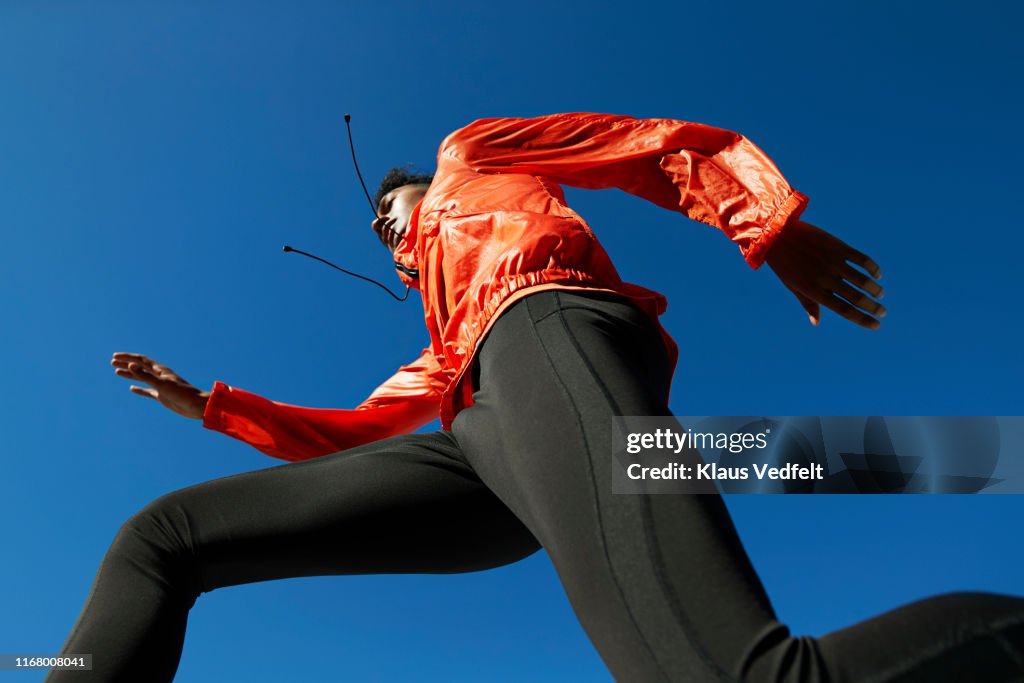 Sportsman running against clear blue sky during sunny day