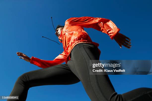 sportsman running against clear blue sky during sunny day - orange jacket stock pictures, royalty-free photos & images