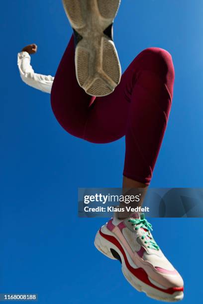 sportswoman jumping against clear blue sky - sports shoe stock-fotos und bilder