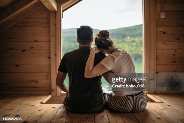 couple embracing in cute log cabin - hut stock pictures, royalty-free photos & images