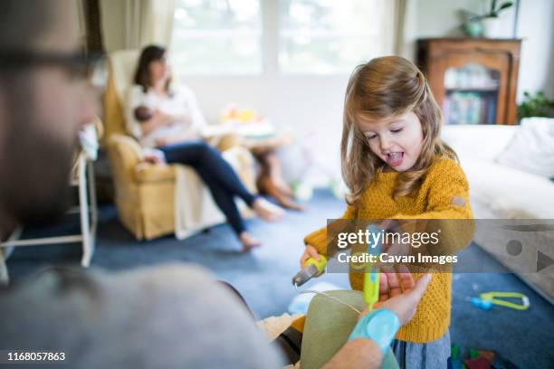 daughter playing doctor, giving dad a shot on arm - adult imagination stock pictures, royalty-free photos & images