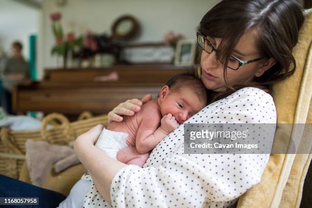 mother holding newborn baby in nursery - new mother stock pictures, royalty-free photos & images