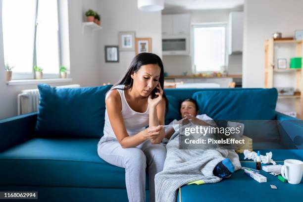 mother calling doctor on the phone because her sick little boy - child illness stock pictures, royalty-free photos & images