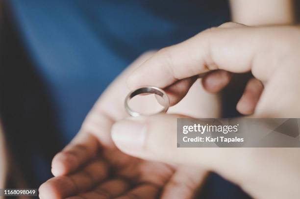 a young couple's hands holding a wedding ring, a concept of divorce - marriage separation stock pictures, royalty-free photos & images