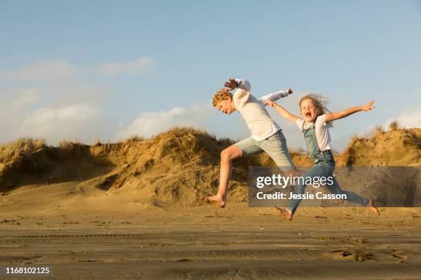 brother and sister practicing long jump on the beach at dusk - mens long jump stockfoto's en -beelden