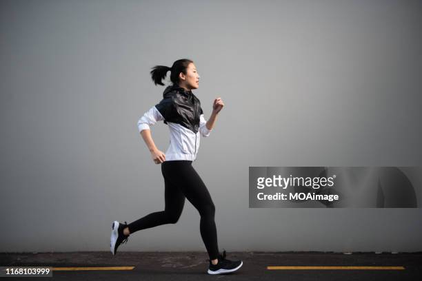 a young asian woman in sportswear is exercising - jogster stockfoto's en -beelden