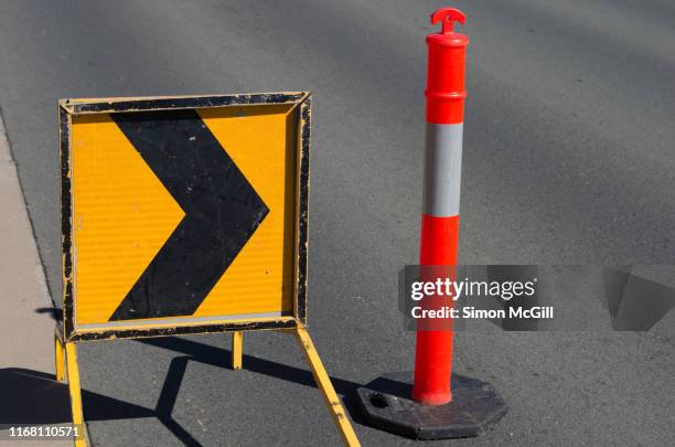 right traffic arrow/ chevron sign and plastic bollards near roadwork - merging sign stockfoto's en -beelden