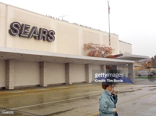 Shopper walks under her umbrella outside a Sears store October 24, 2001 in Niles, IL. Sears, Roebuck and Co. Said Wednesday, October 24, 2001 that it...