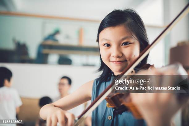 家でバイオリンを弾くアジアの小さな女の子。 - music choice ストックフォトと画像