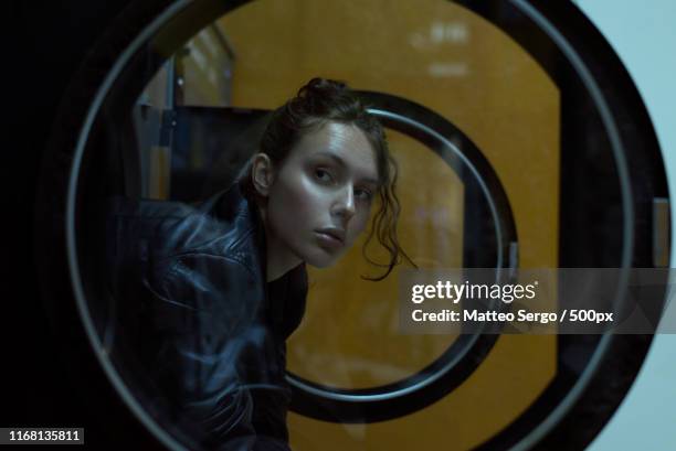 woman waiting at laundromat - wäscherei stock-fotos und bilder