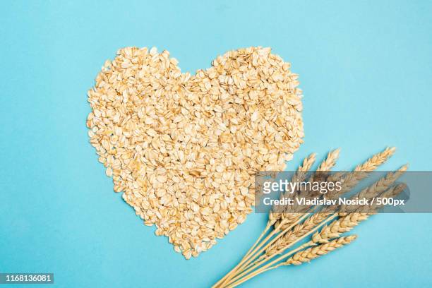 oats or oat flakes in shape of heart on blue background - oat ear stock pictures, royalty-free photos & images