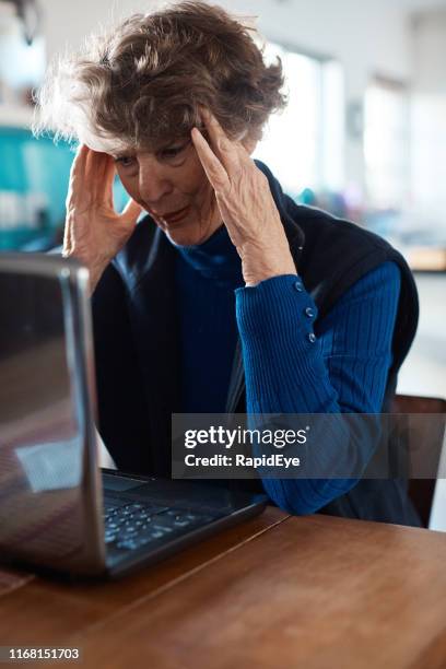 verontruste senior vrouw, hoofd in handen, met laptop - technofobie stockfoto's en -beelden