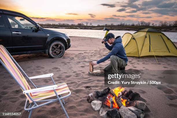 tourist chopping wood for campfire - axe stock pictures, royalty-free photos & images