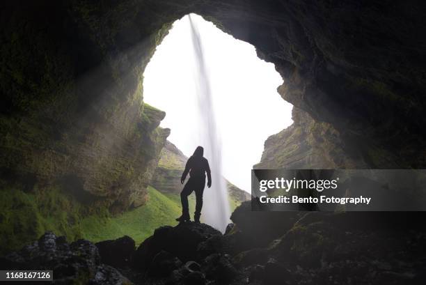 hiker at majestic kvernufoss waterfall in iceland - cave man foto e immagini stock